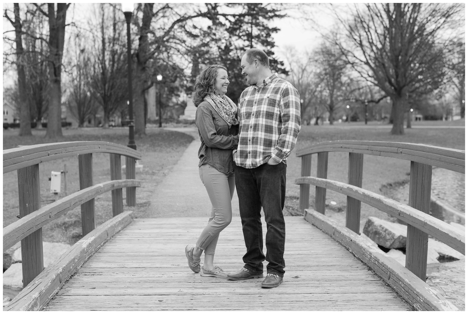 black and white photo of an engaged couple lovingly looking at each other on a bridge at schiller park in columbus ohio in german village.