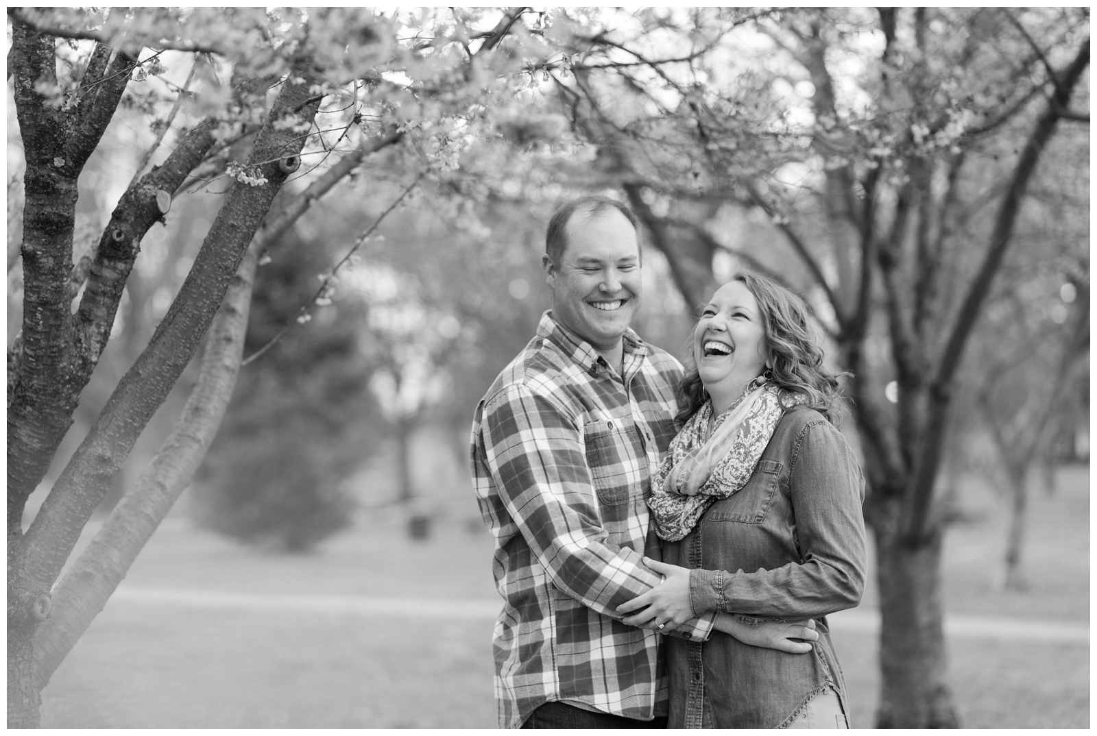 black and white photo of a happy engaged couple laughing at each other 