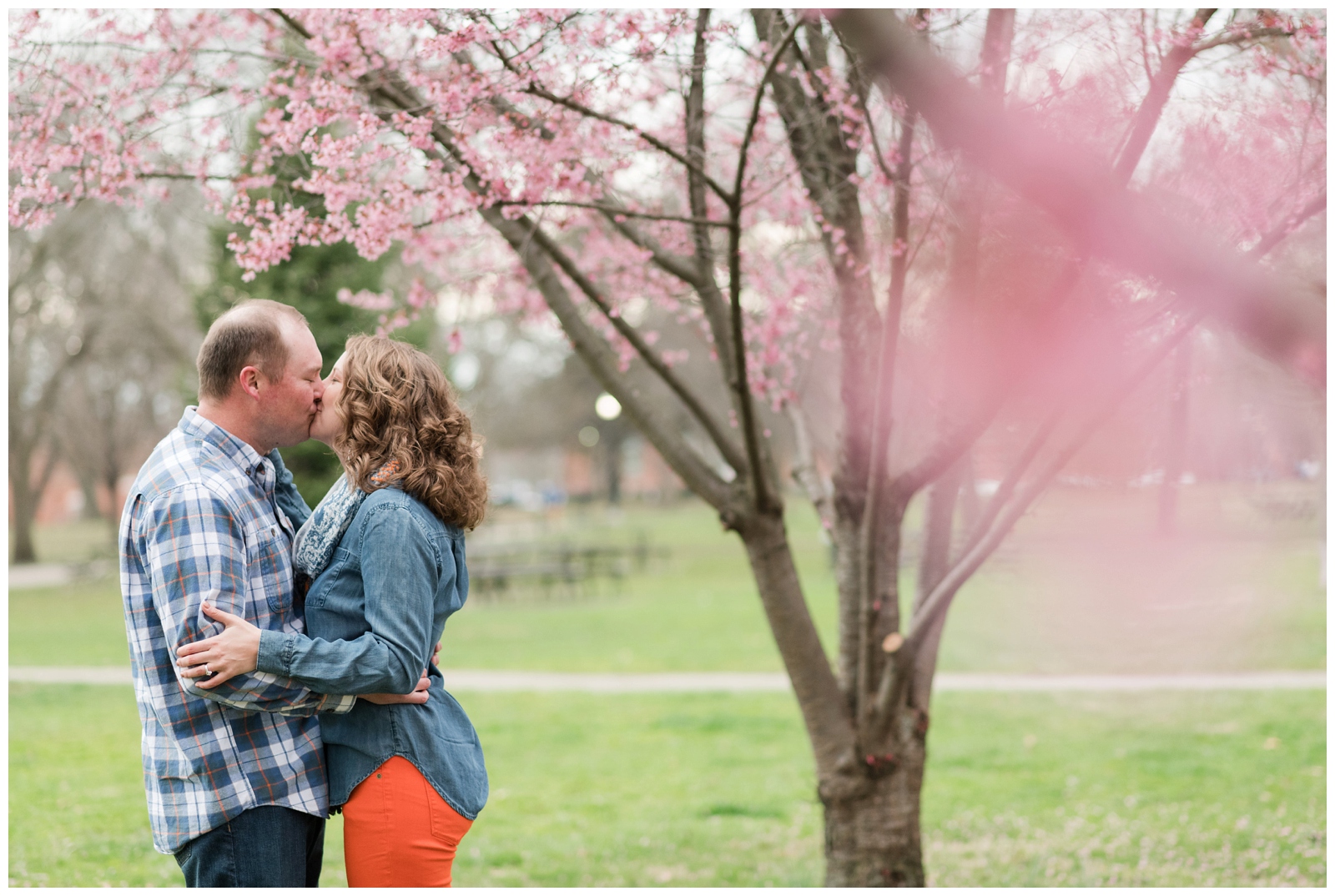 Couple kisses among spring redbud trees in german village at schiller Park by pipers Photography