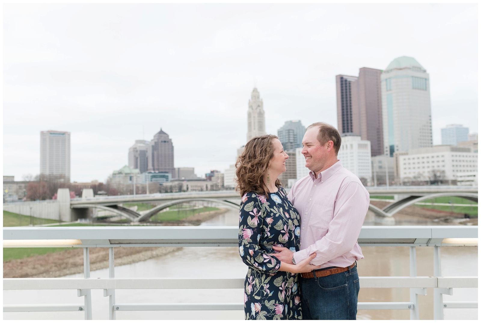 a happy couple cheerfully looks at each other while embracing one-another with the Columbus city skyline behind them