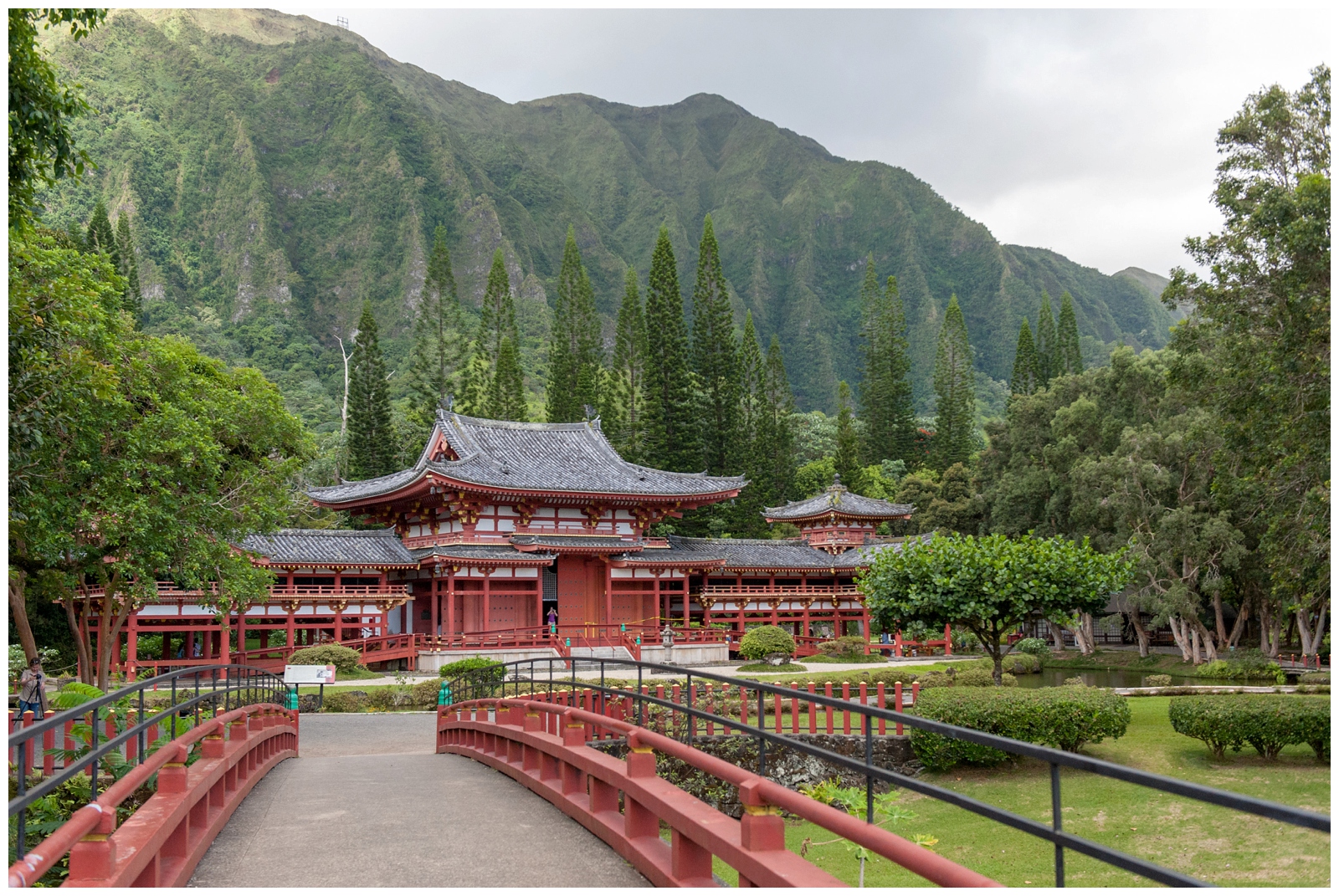 landscape photo of Byodo-in Temple in the valley of the temples memorial park with the main walkway leading you into the temple surrounded by trees and mountains 