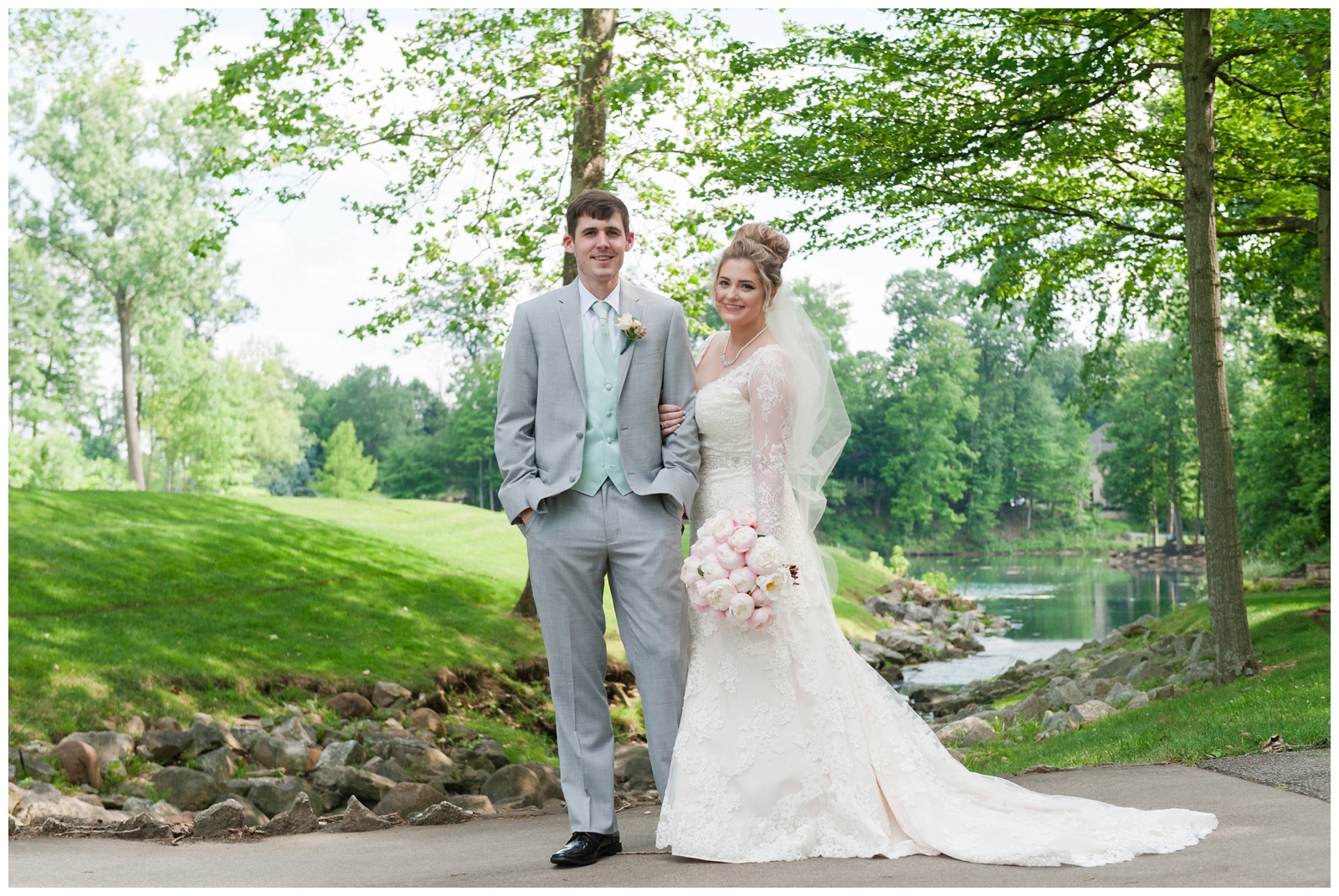 bride and groom looking at the camera with a pink peony bouquet and the wedgewood golf and country club behind them. 