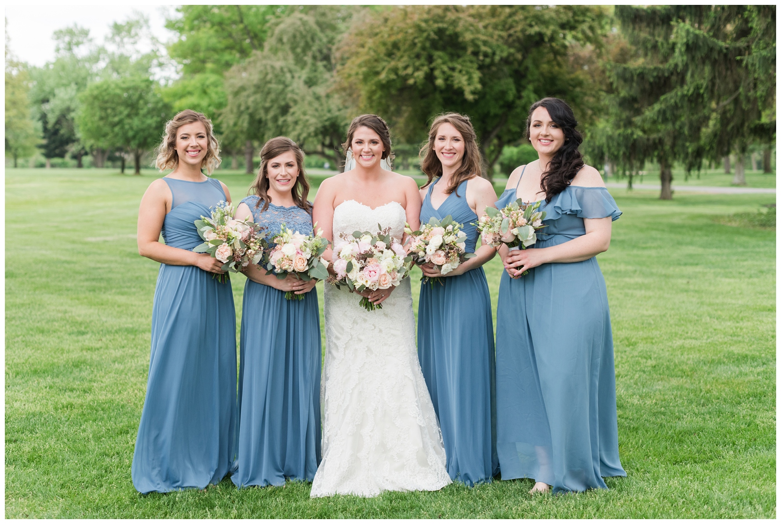 bridesmaids in blue gowns with pink and white bouquets pose with bride on green of Brookside Golf and Country Club