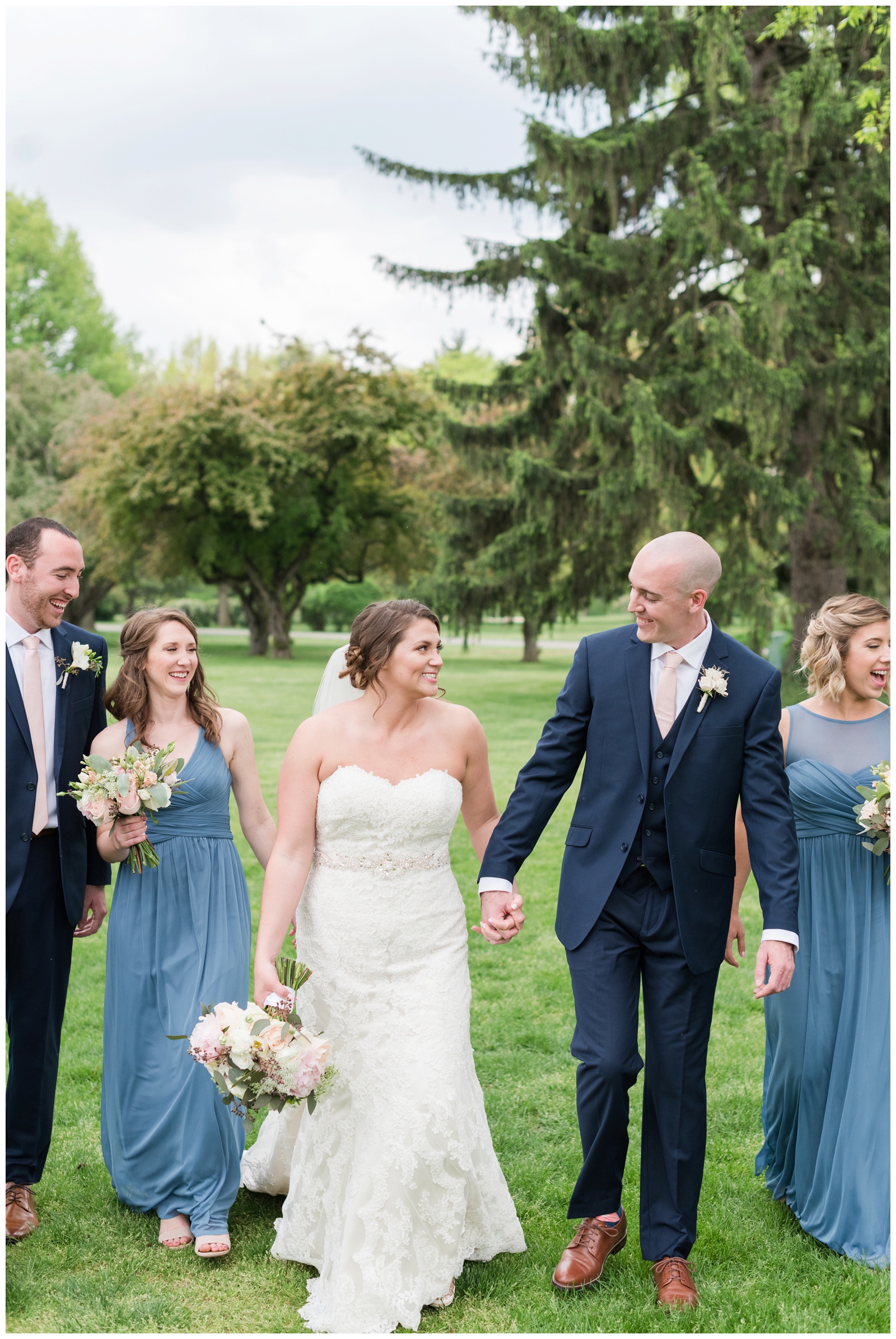 bride and groom smile at each other while walking with bridal party at Brookside Golf and Country Club