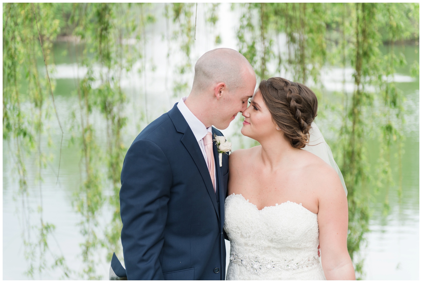 bride and groom touch noses while bride smiles at groom under willow tree at Brookside Golf and Country Club
