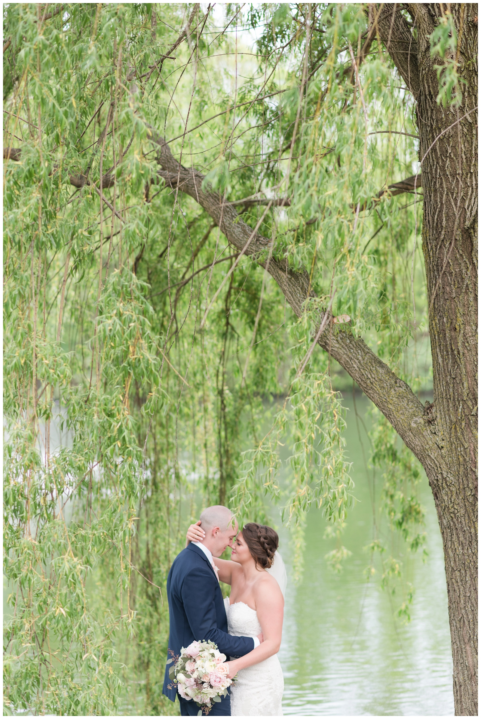 bride holds groom close to her under willow tree during Ohio wedding day at Brookside Golf and Country Club