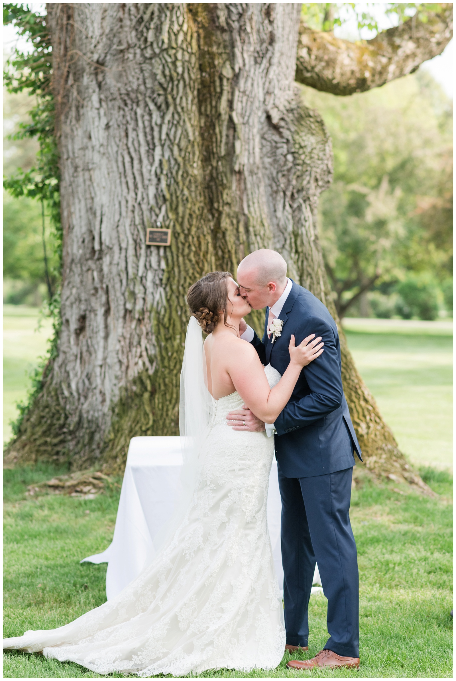 bride and groom have first kiss as husband and wife by tree on Brookside Golf and Country Club