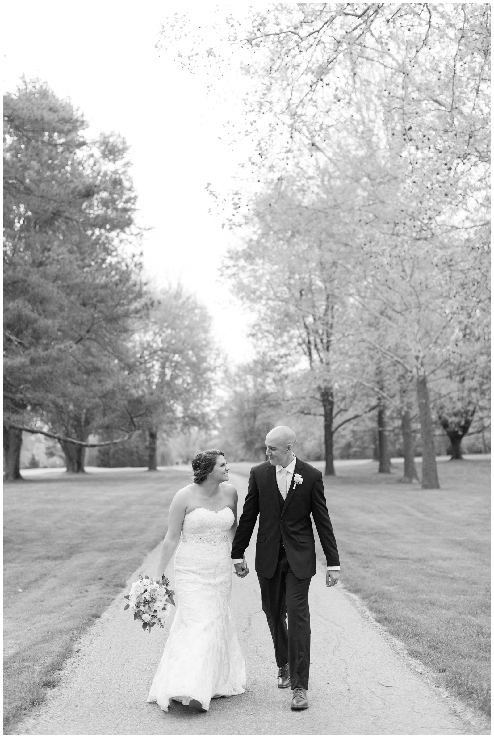 black and white wedding portrait of bride and groom holding hands while walking during elegant Brookside Golf and Country Club wedding
