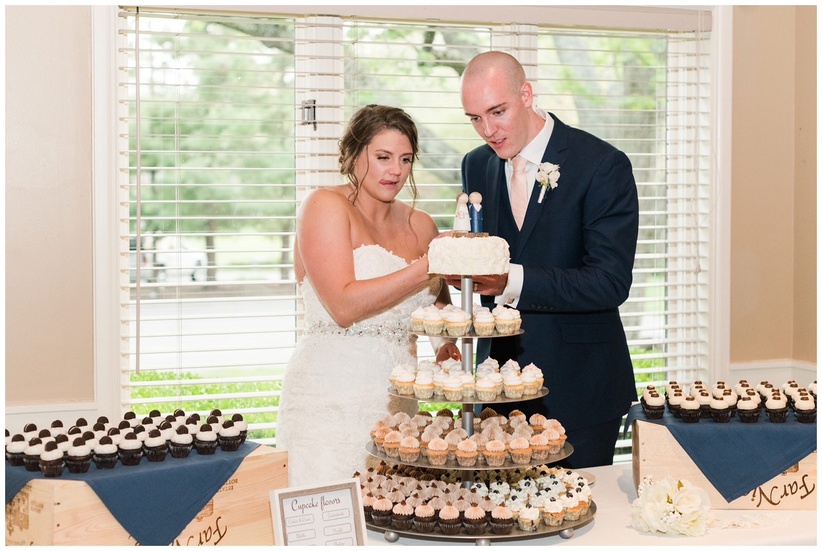 bride and groom cut top tier of wedding cake and cupcake display at Ohio wedding