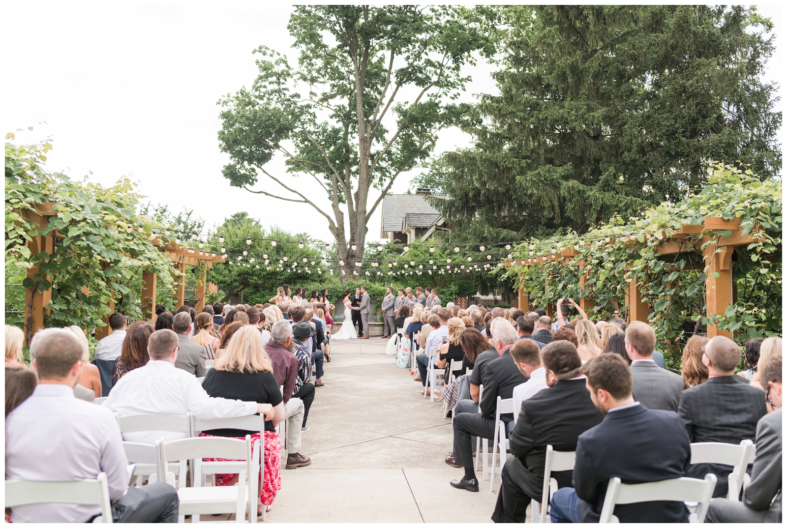 outdoor wedding ceremony with garden lights hanging at The Wells Barn at Franklin Park Conservatory