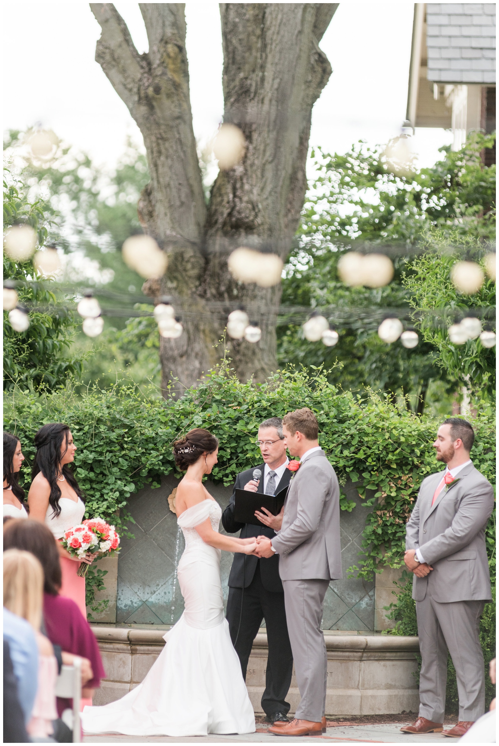 bride and groom listen to officiant during garden wedding ceremony at The Wells Barn