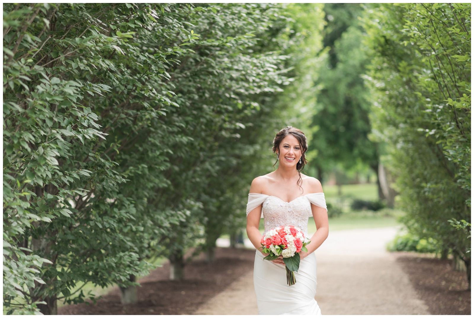 summer bridal portrait of bride in off the shoulders wedding dress with coral and white wedding bouquet
