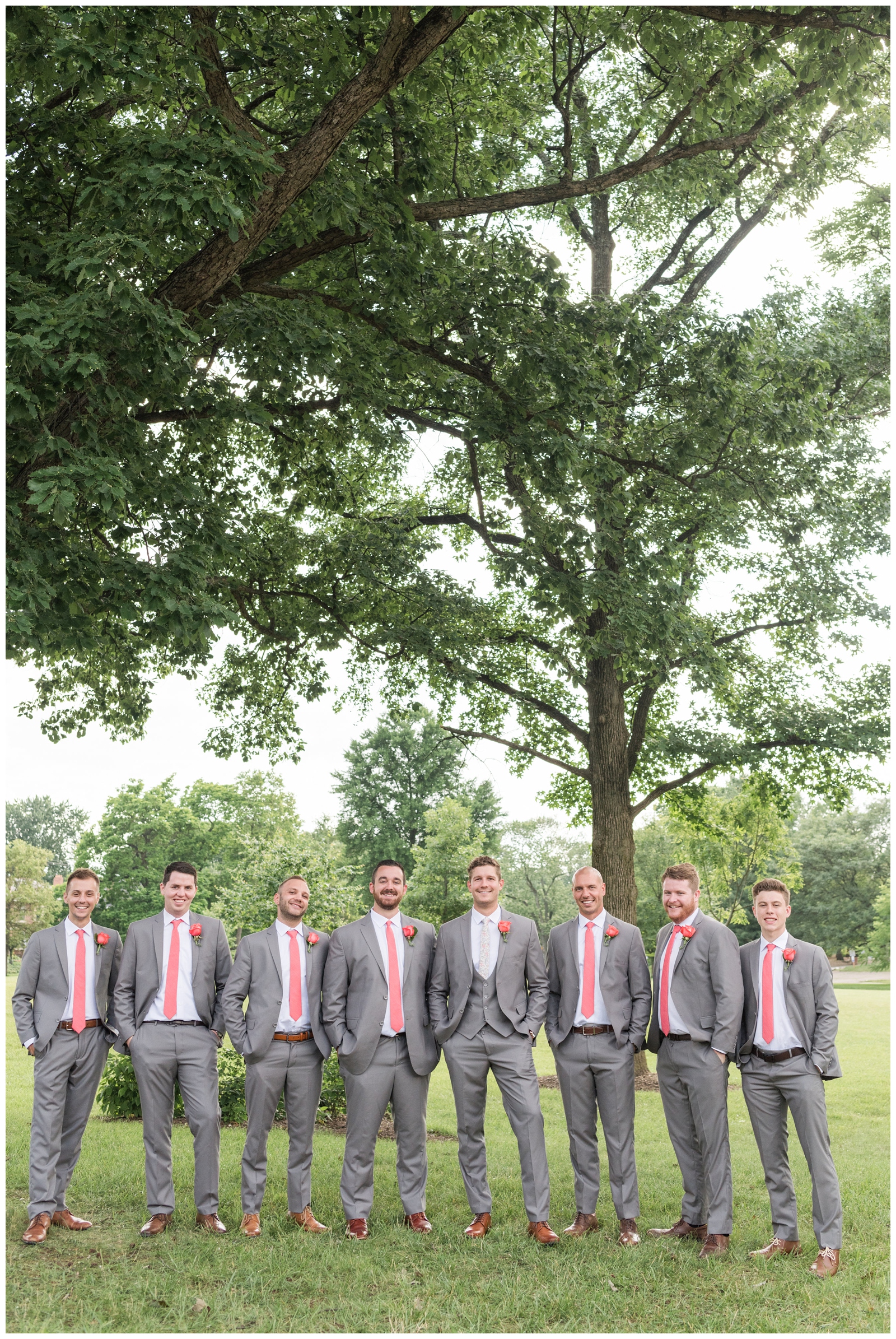 groomsmen in grey suits with pink ties pose at The Wells Barn