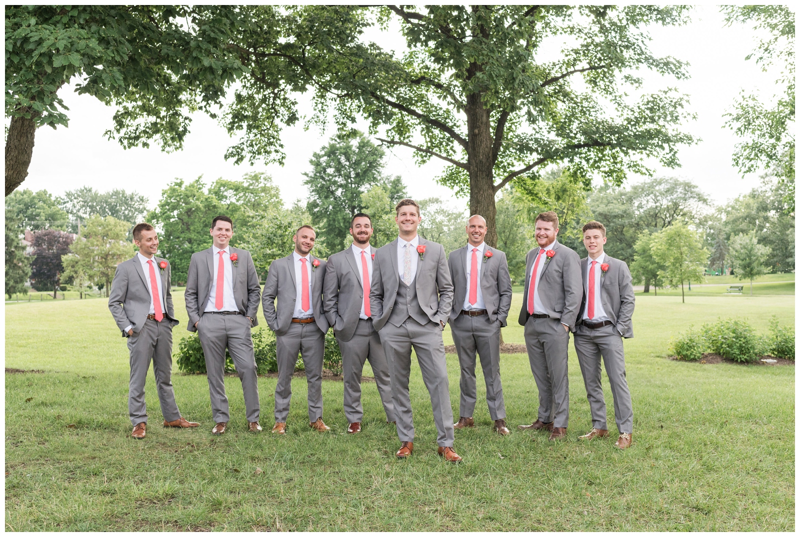 seven groomsmen in grey suits with coral ties pose for Pipers Photography at The Wells Barn