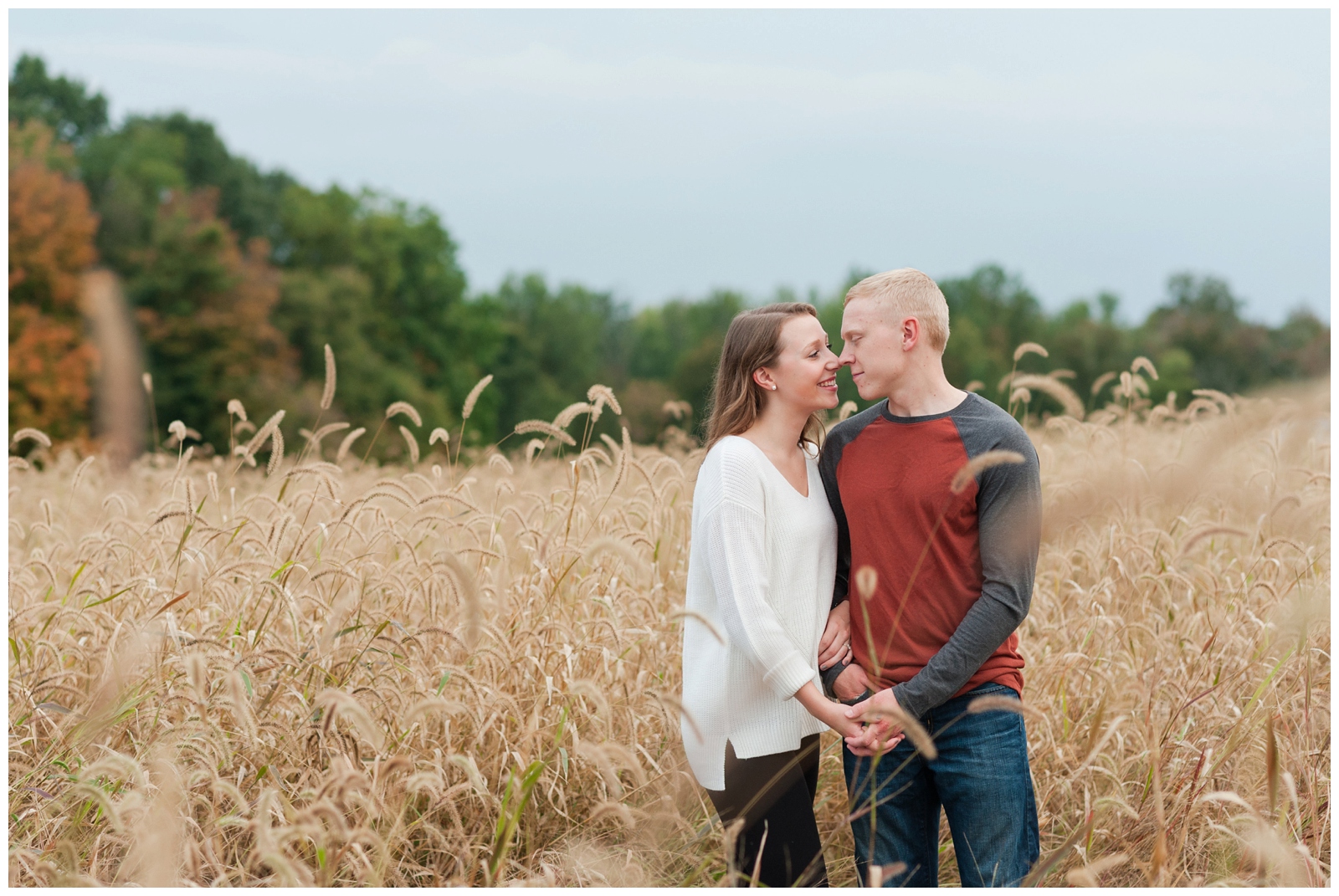engaged couple snuggling in and holding hands in a wheat field during their Country Engagement Session Sunbury Ohio