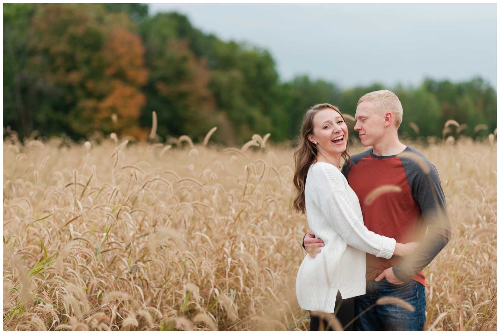 engaged girl laughing at the camera while engaged man looks at her Country Engagement Session Sunbury Ohio