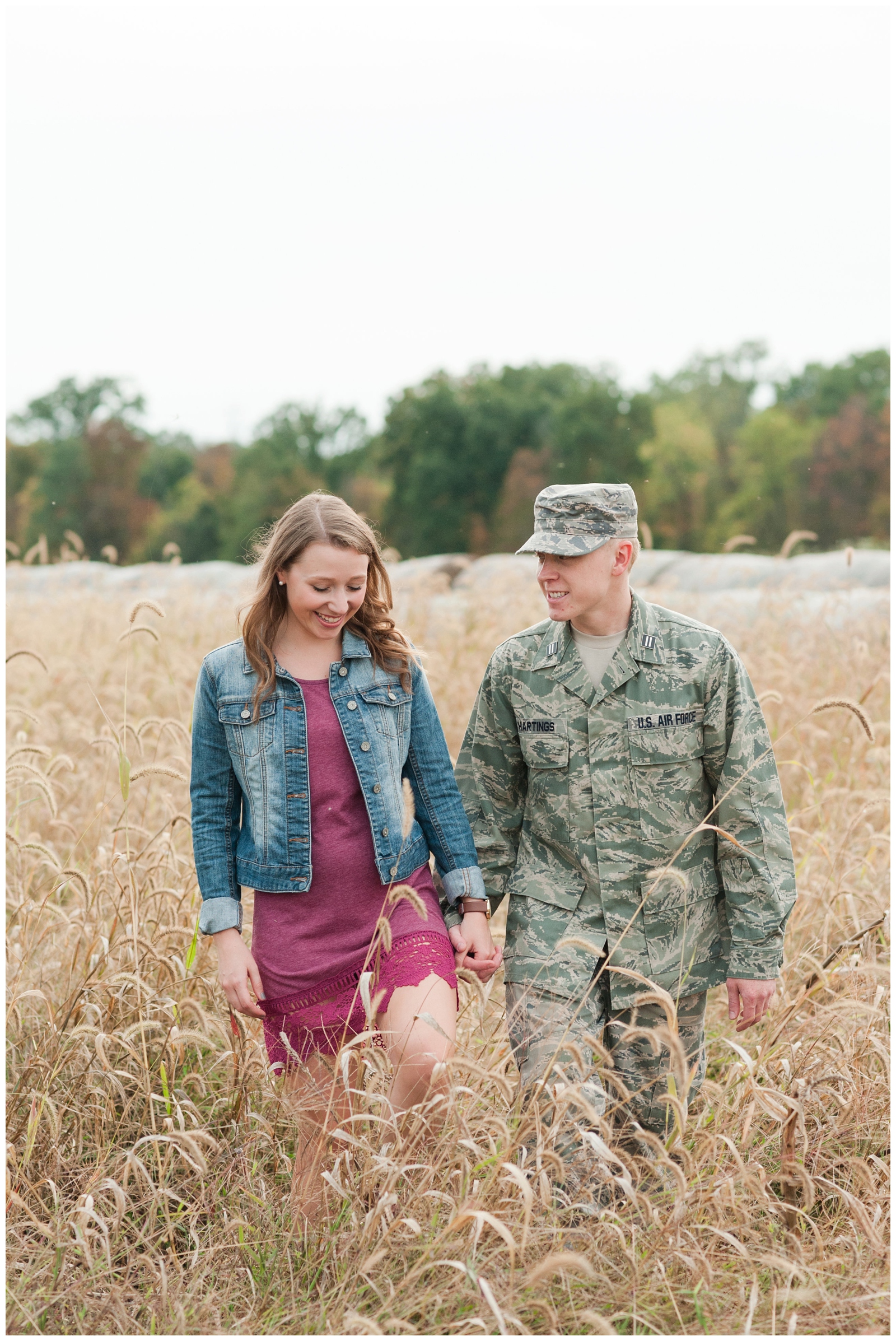 couple happily laughing and smiling while casually walking through wheat field during their country engagement session in sunbury ohio 