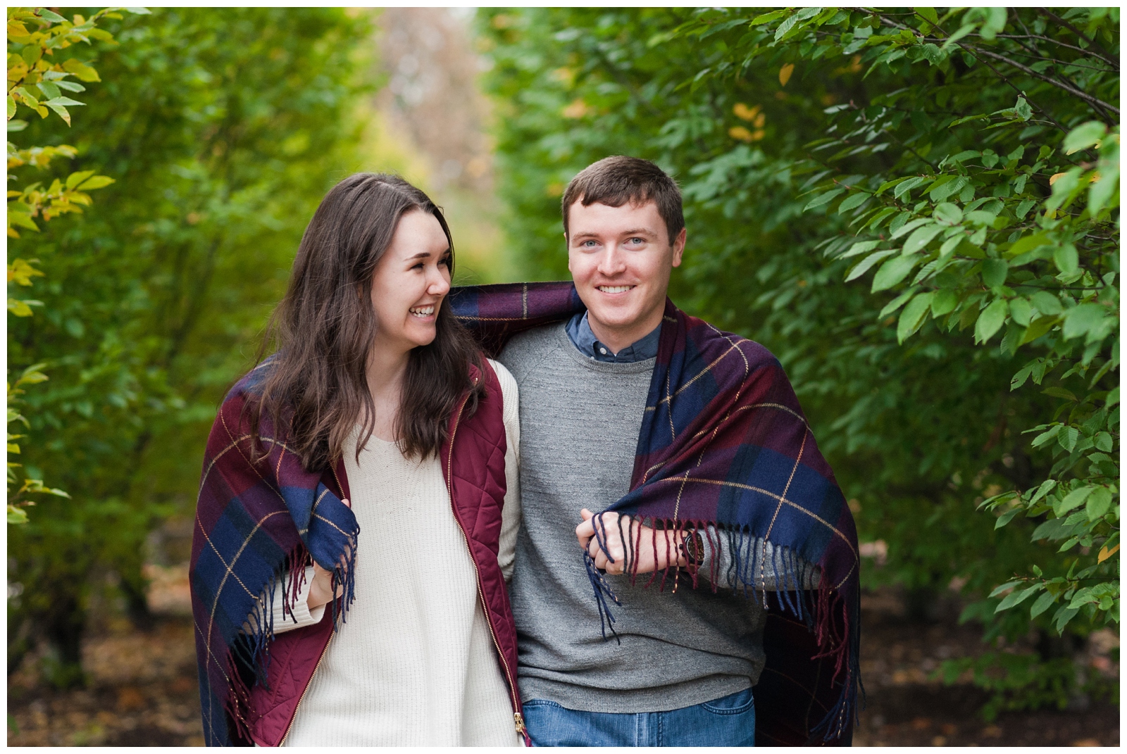 man and woman walking together under a blanket during their engagement session at the wells barn at franklin park conservatory 
