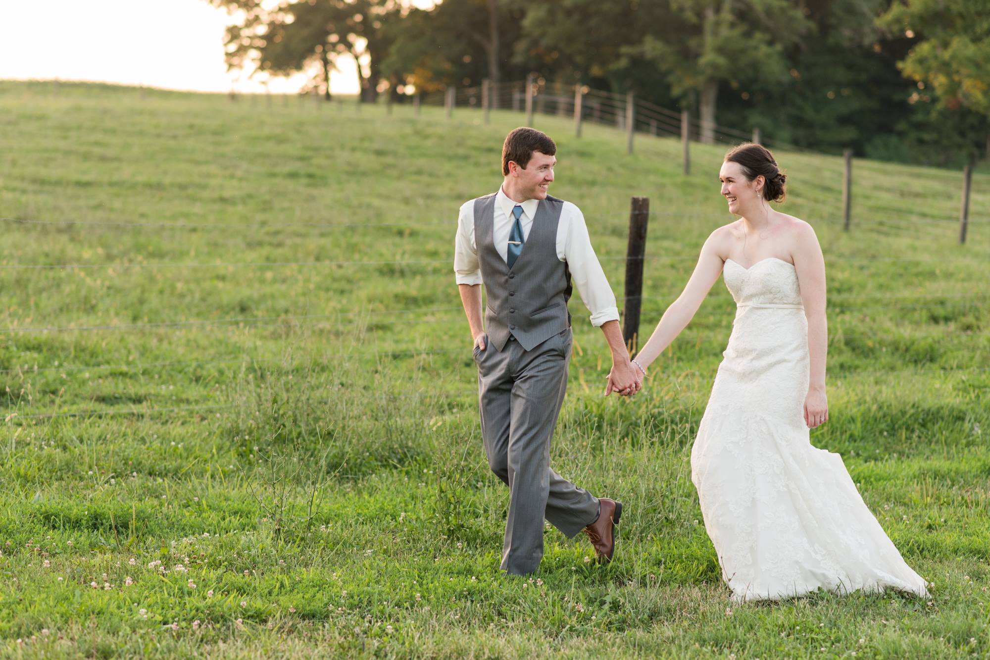 bride and groom happily walking together outside in their elegant country wedding 