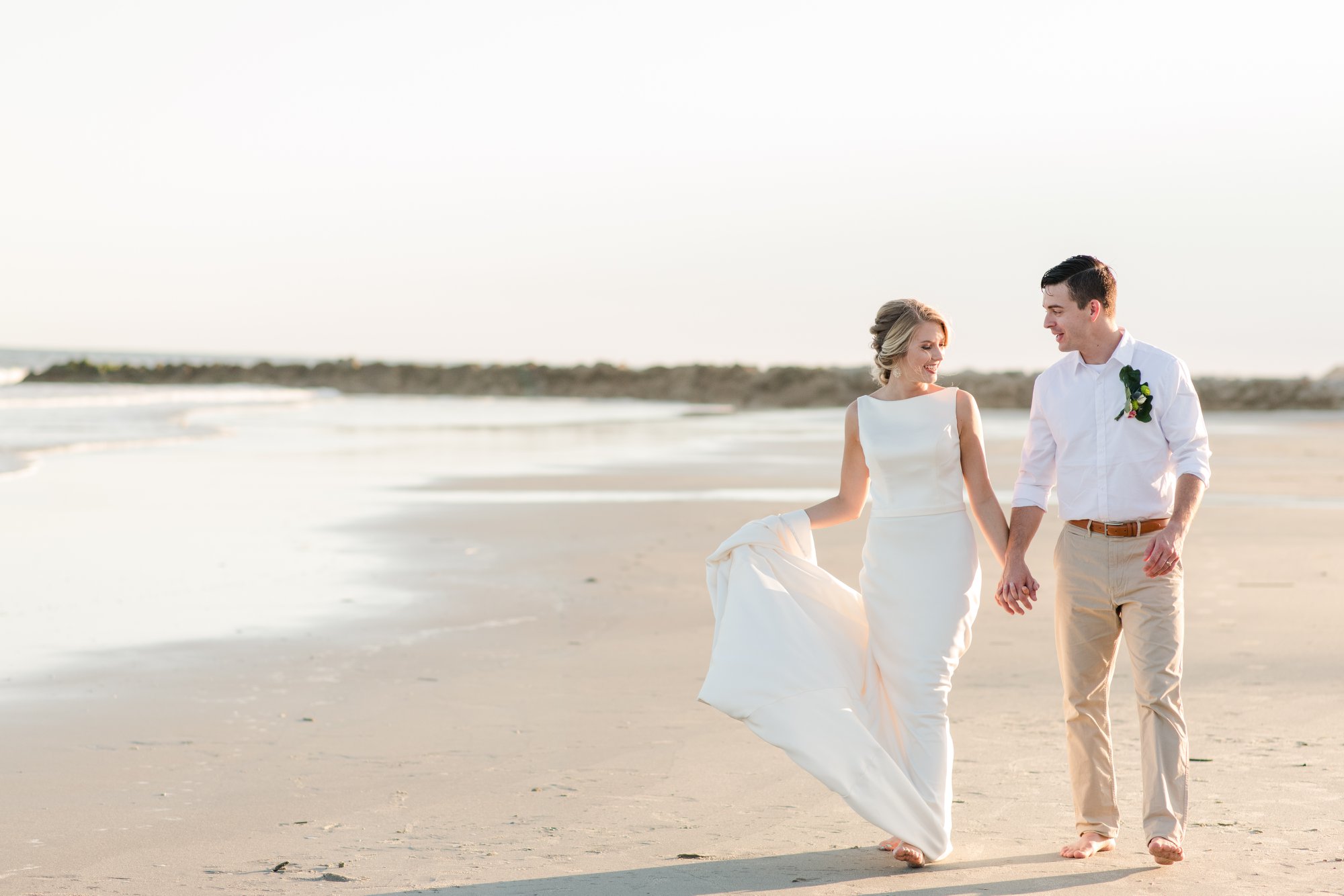 bride and groom walking along the ocean at the beach in folly beach south carolina 
