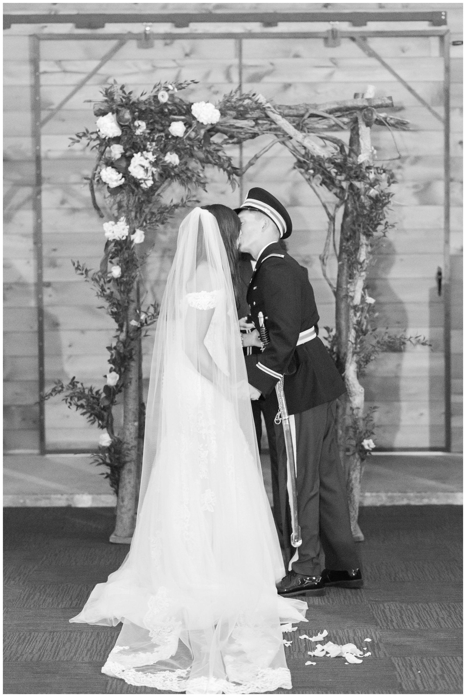 black and white image of bride and groom kissing during their wedding ceremony 