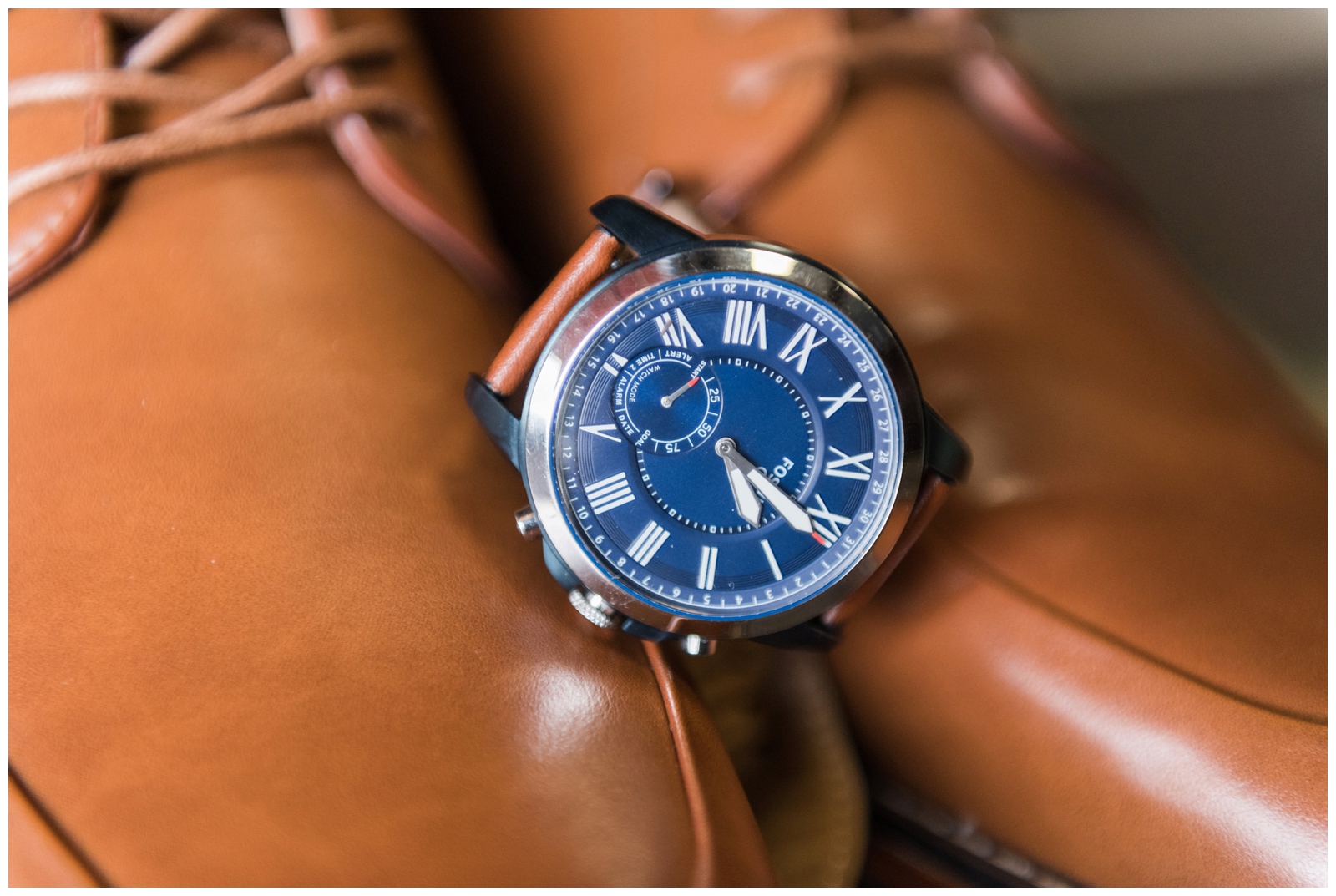 groom's watch with blue face rests on brown shoes