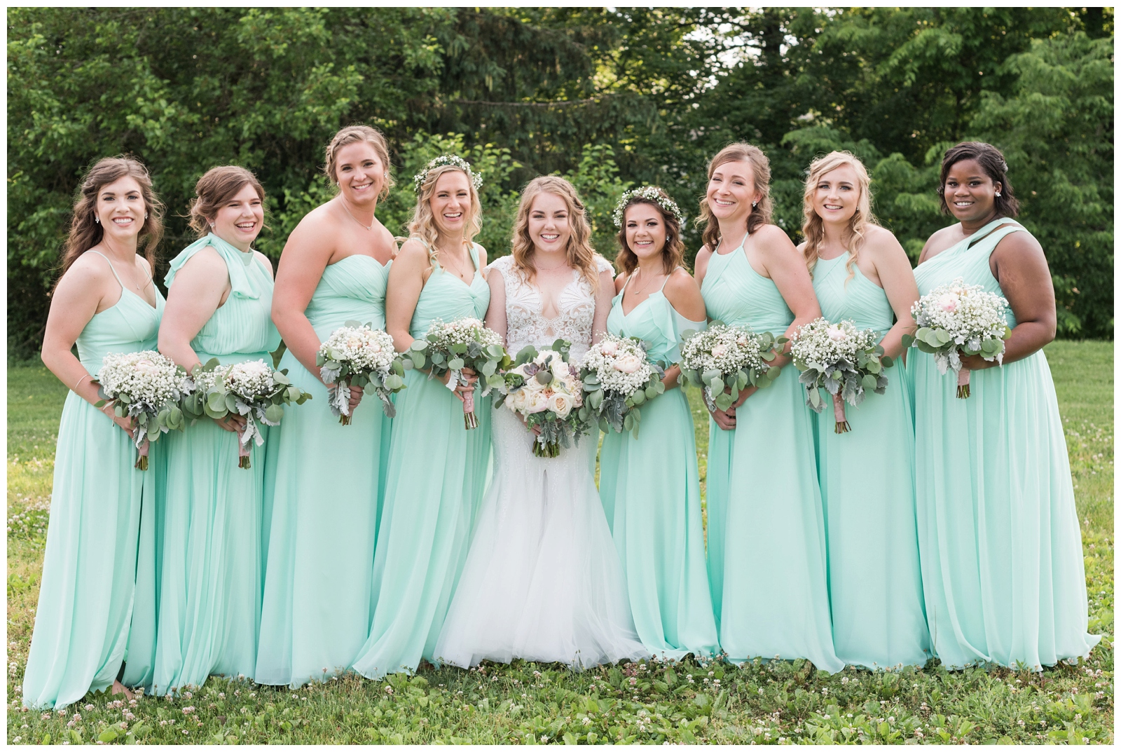bridesmaids wearing mint green dresses smile with bride while holding white bouquets