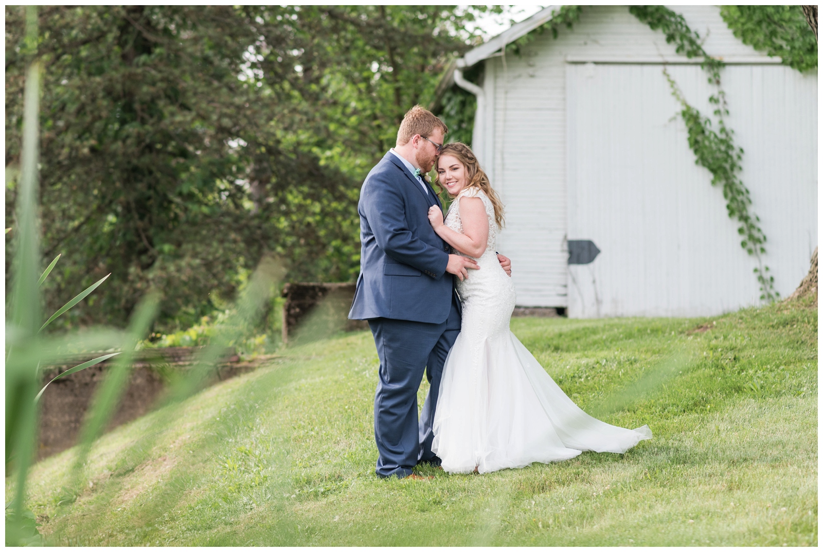bride snuggles into groom near white barn at EagleSticks Golf Club