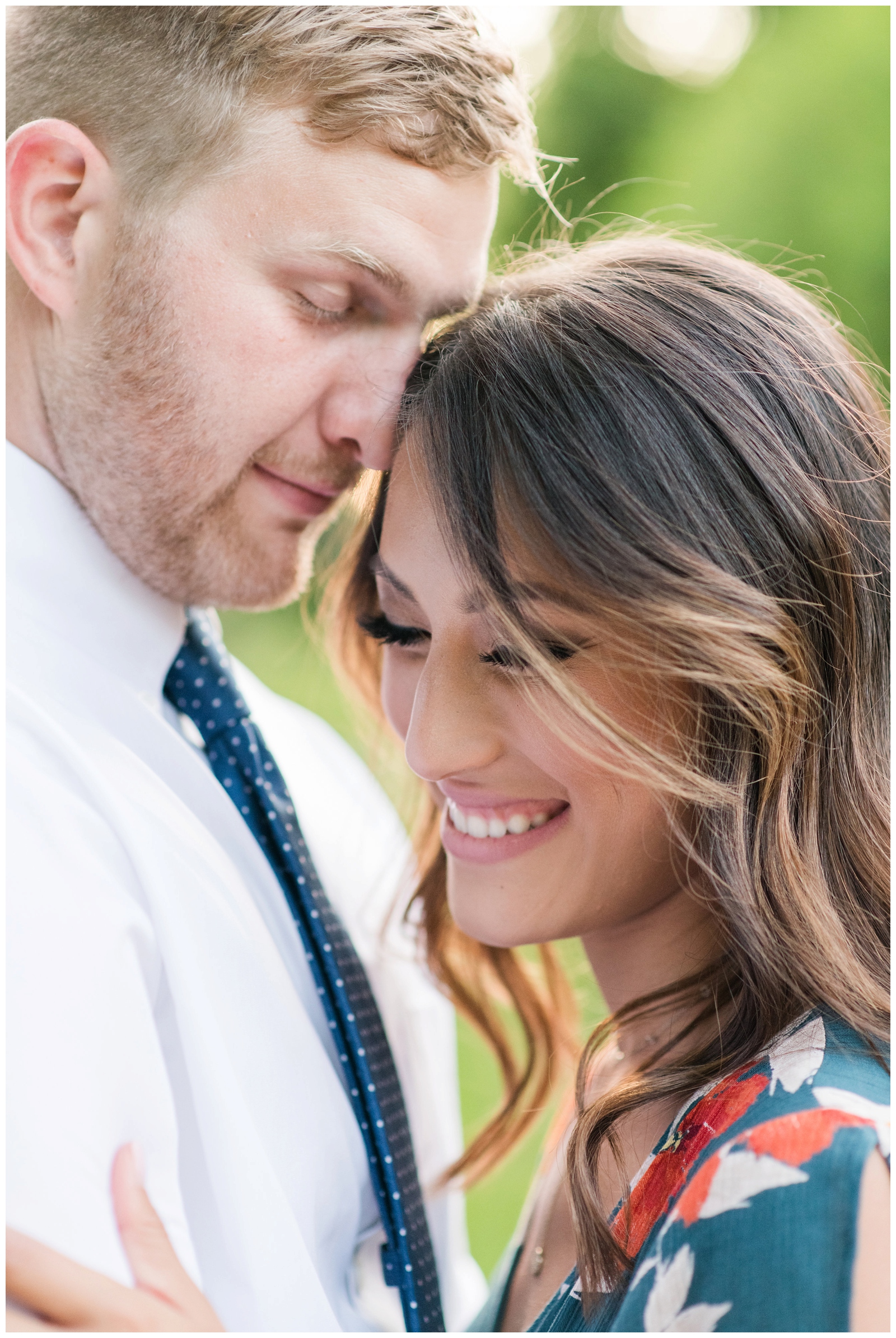 close up image of engaged couple hugging and embracing while looking away from the camera and smiling 