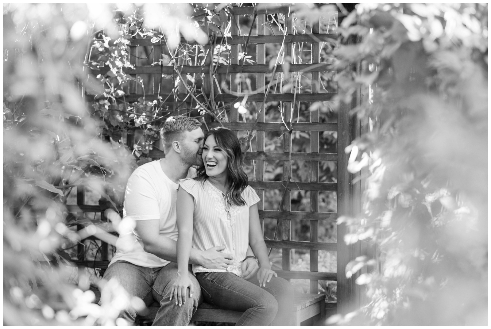 engaged couple laughing away from the camera in black and white in a garden setting 
