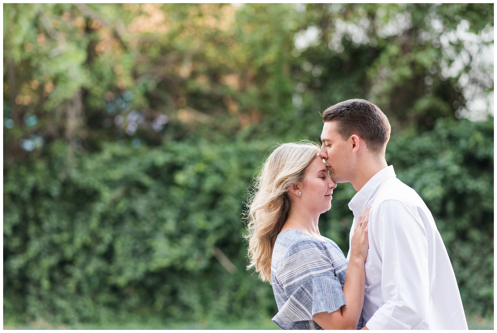 groom kisses fiancee on the forehead during Park of Roses engagement session