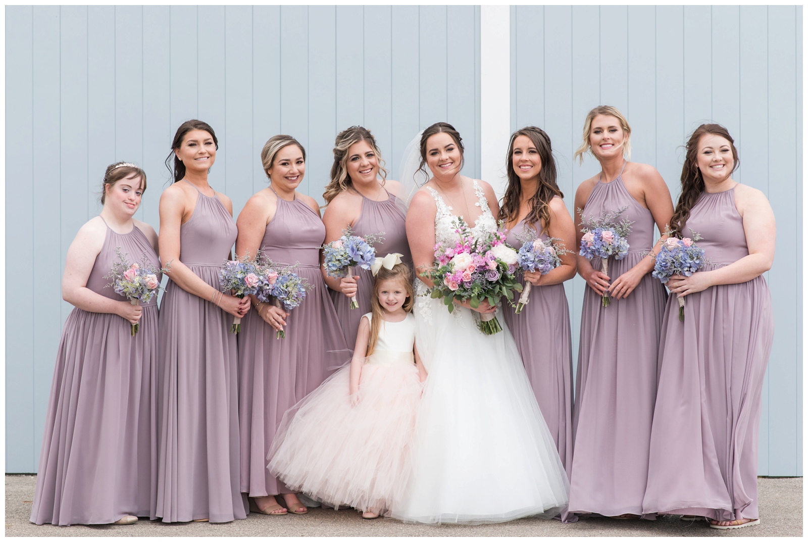 seven bridesmaids in pale pink dresses with flower girl and bride pose on Pretty Prairie Farms
