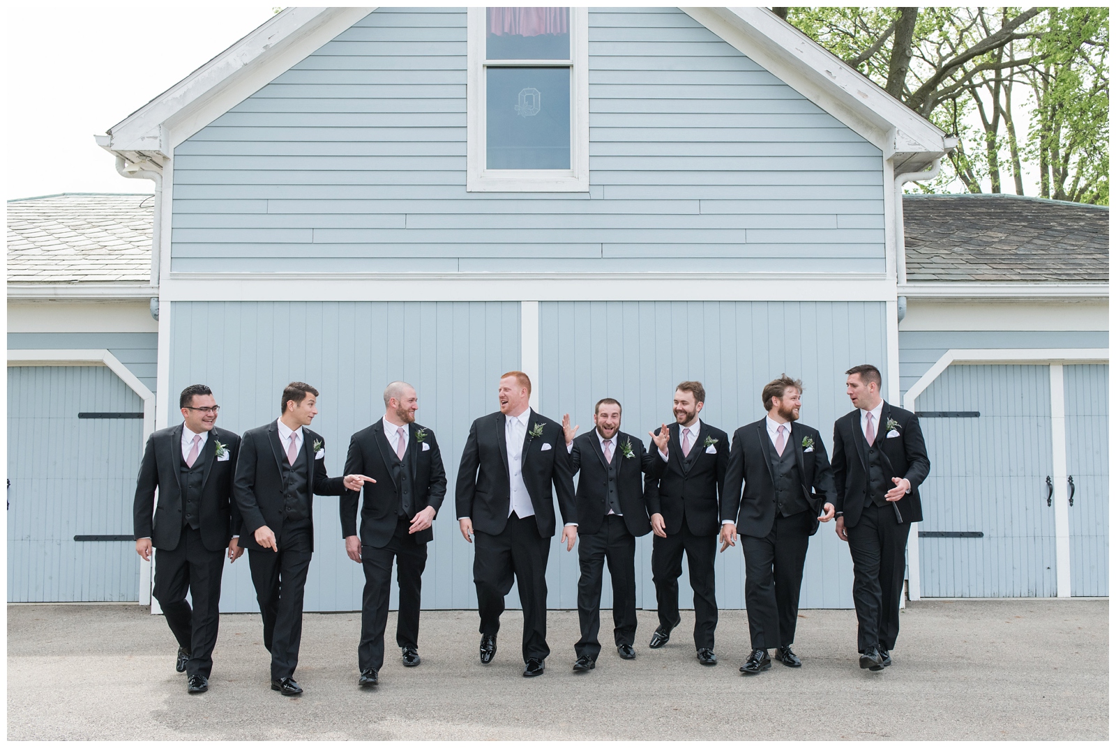 groomsmen in black talk and walk during Ohio wedding portraits