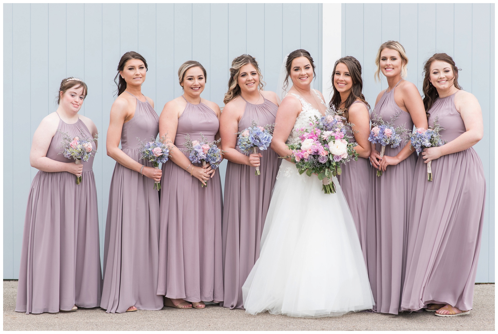7 bridesmaids hold pastel wedding bouquets with bride at Pretty Prairie Farms