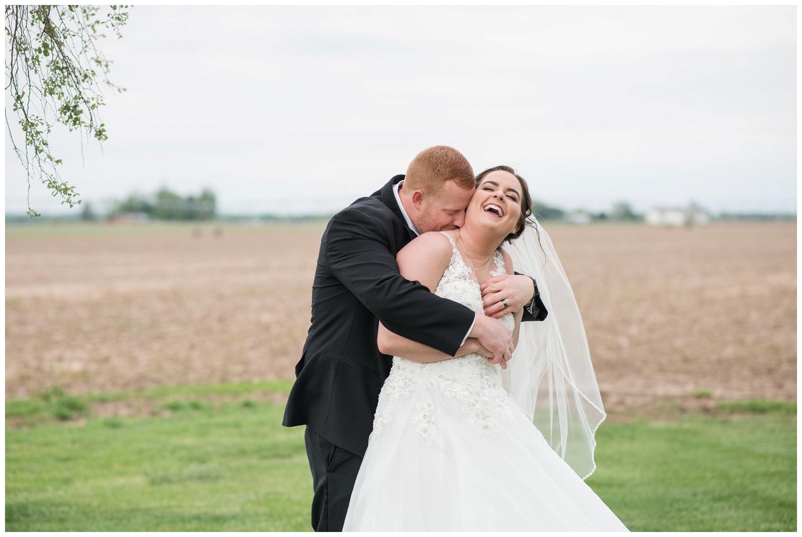 groom makes bride laugh during wedding portraits on farm