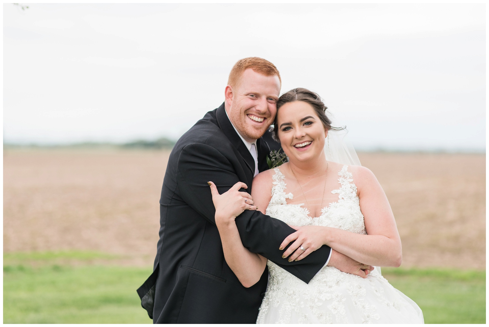 newly married couple laugh during wedding portraits on farm