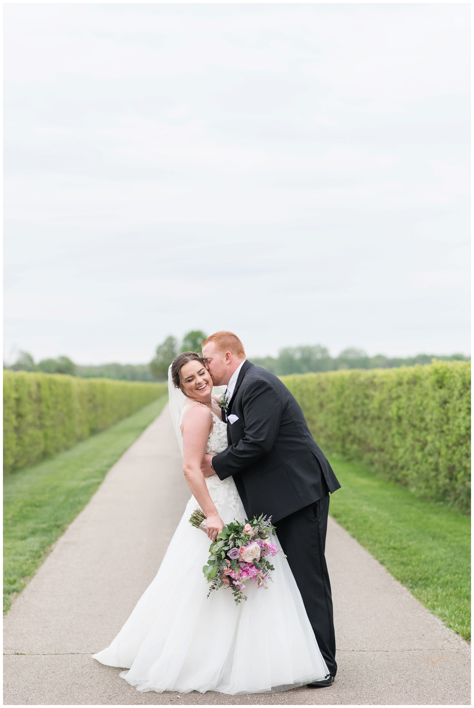 Groom kisses bride during wedding portraits at Pretty Prairie Farms