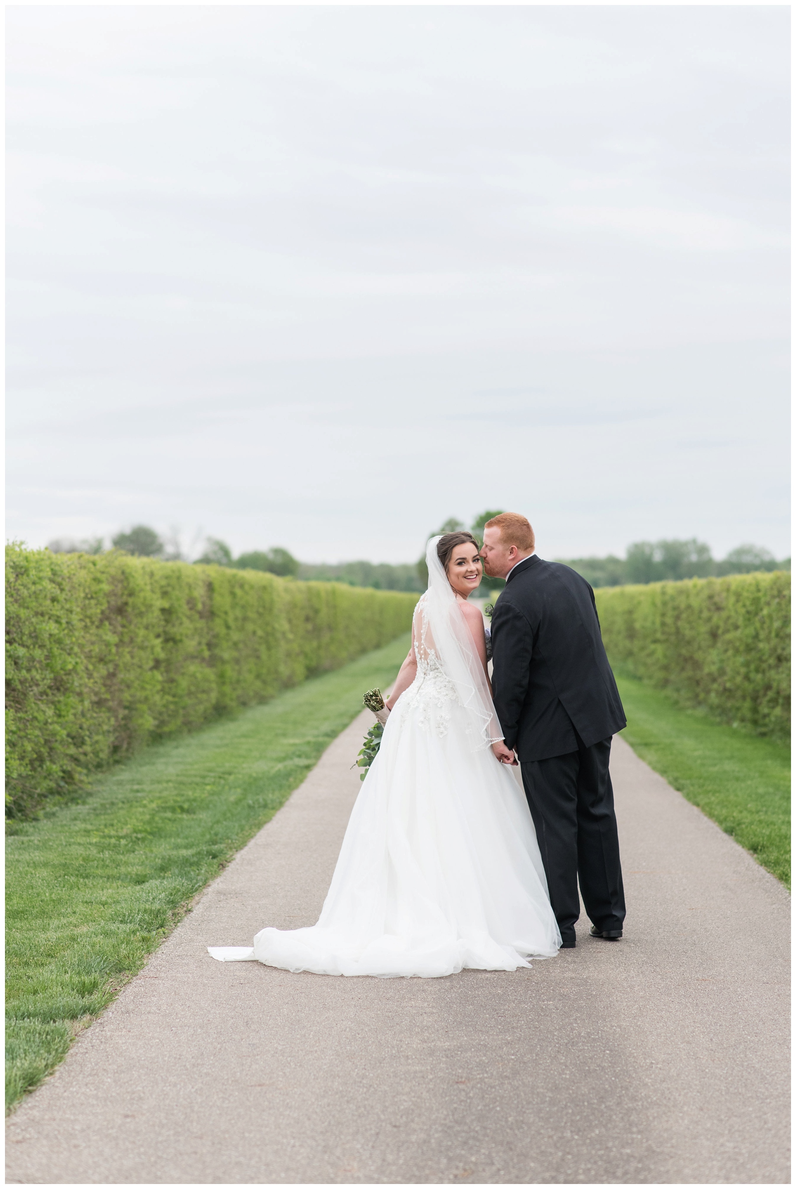 Ohio bride and groom pose along road at Pretty Prairie Farms