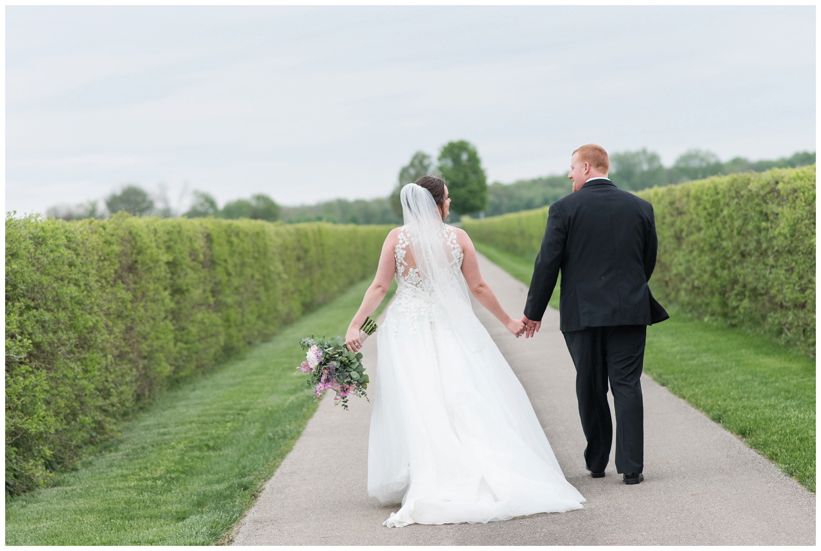 Bride and groom walk up road at Pretty Prairie Farms in Urbana Ohio