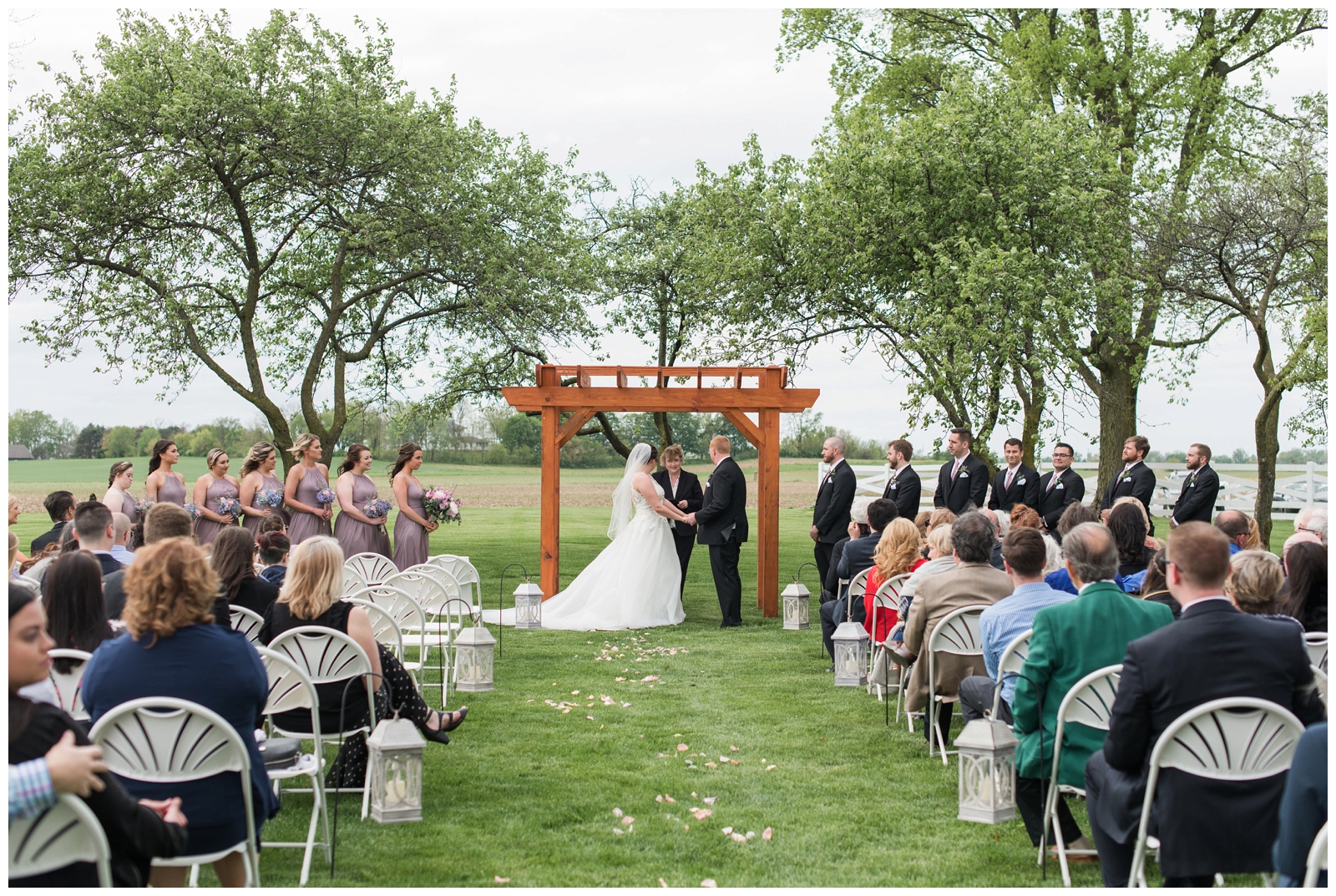 bride and groom exchange vows under arbor on Pretty Prairie Farms