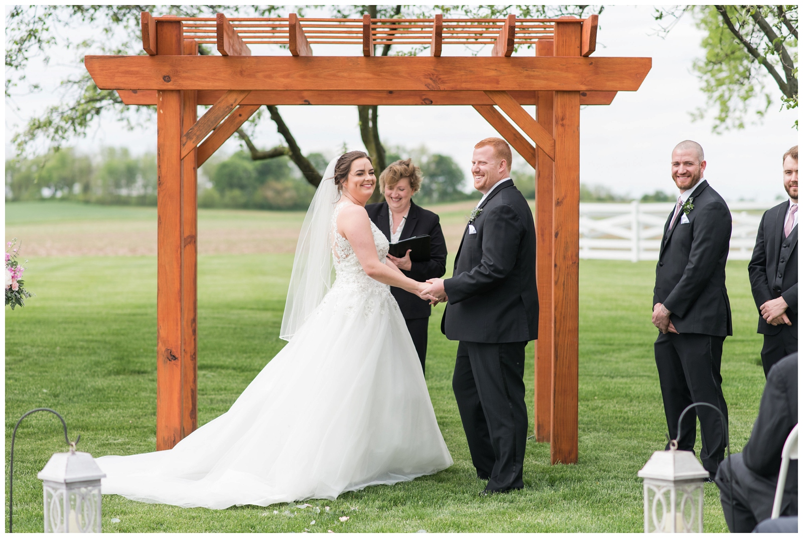 bride and groom exchange vows at Pretty Prairie Farms with bridal party beside them