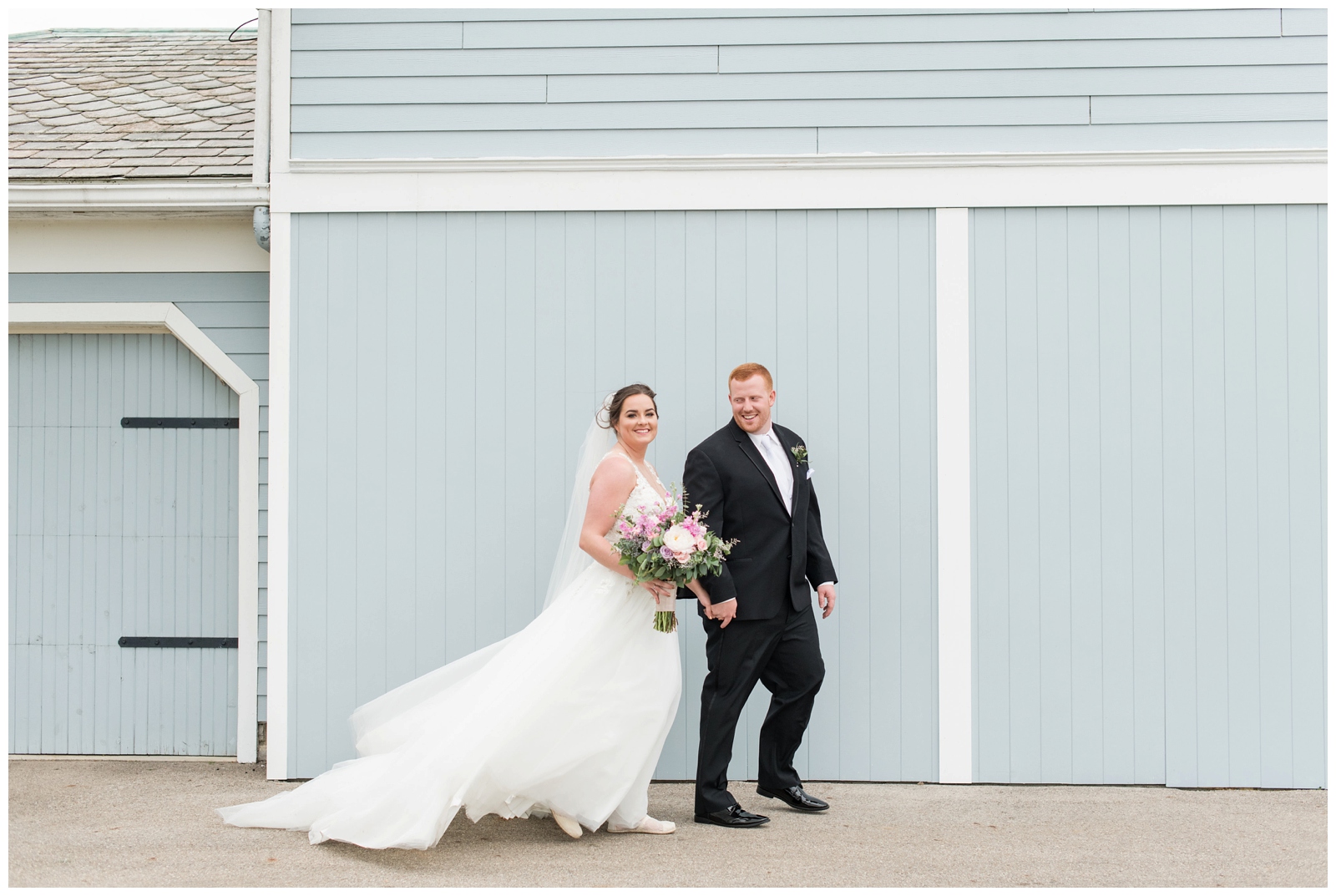 Bride and groom walk near blue wall at Pretty Prairie Farms