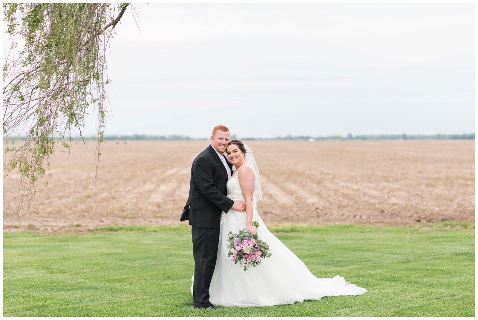 bride and groom embrace during portraits by farm fields