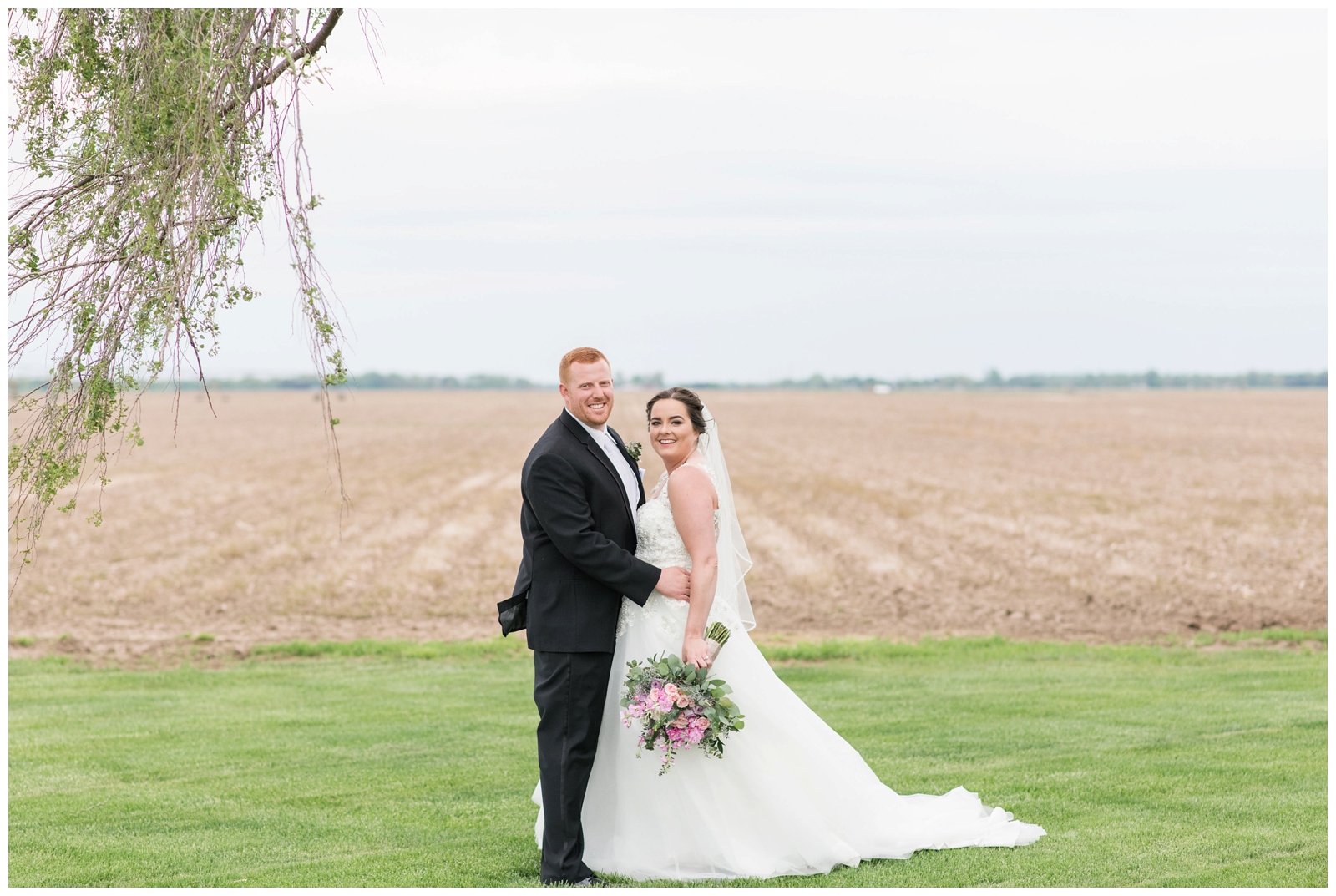 bride and groom hug during portraits by farm field at Pretty Prairie Farms