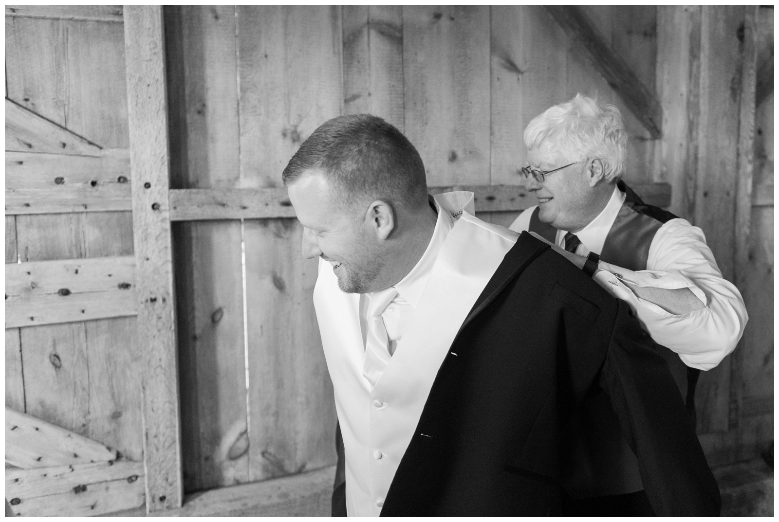 groom gets into jacket at Pretty Prairie Farms with help of dad
