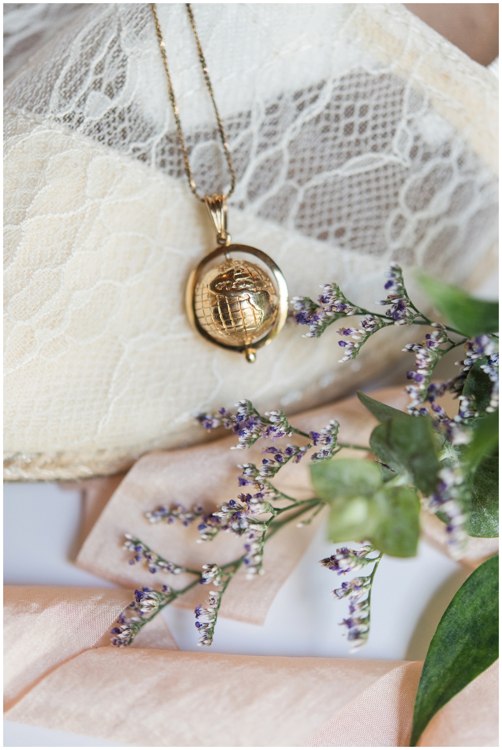 gold globe necklace for bride lays on lace TOMS 