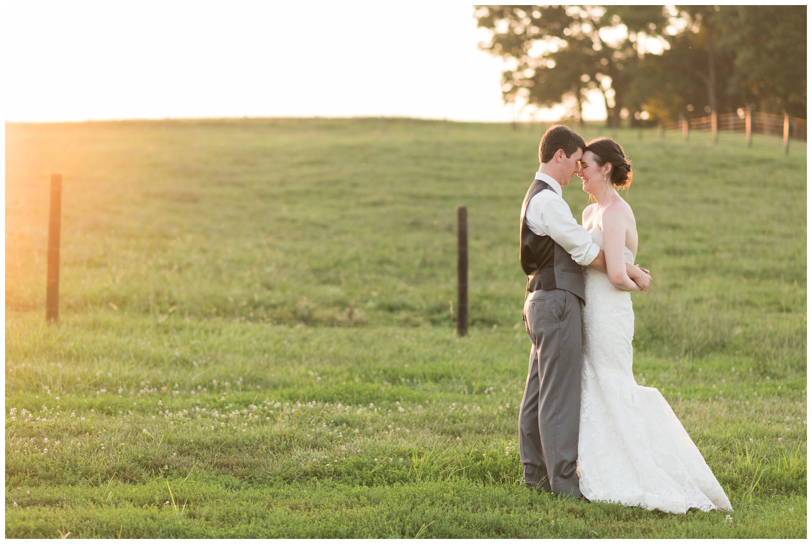 sophisticated bride and groom on their elegant wedding day in a field at sunset looking at eachother hugging