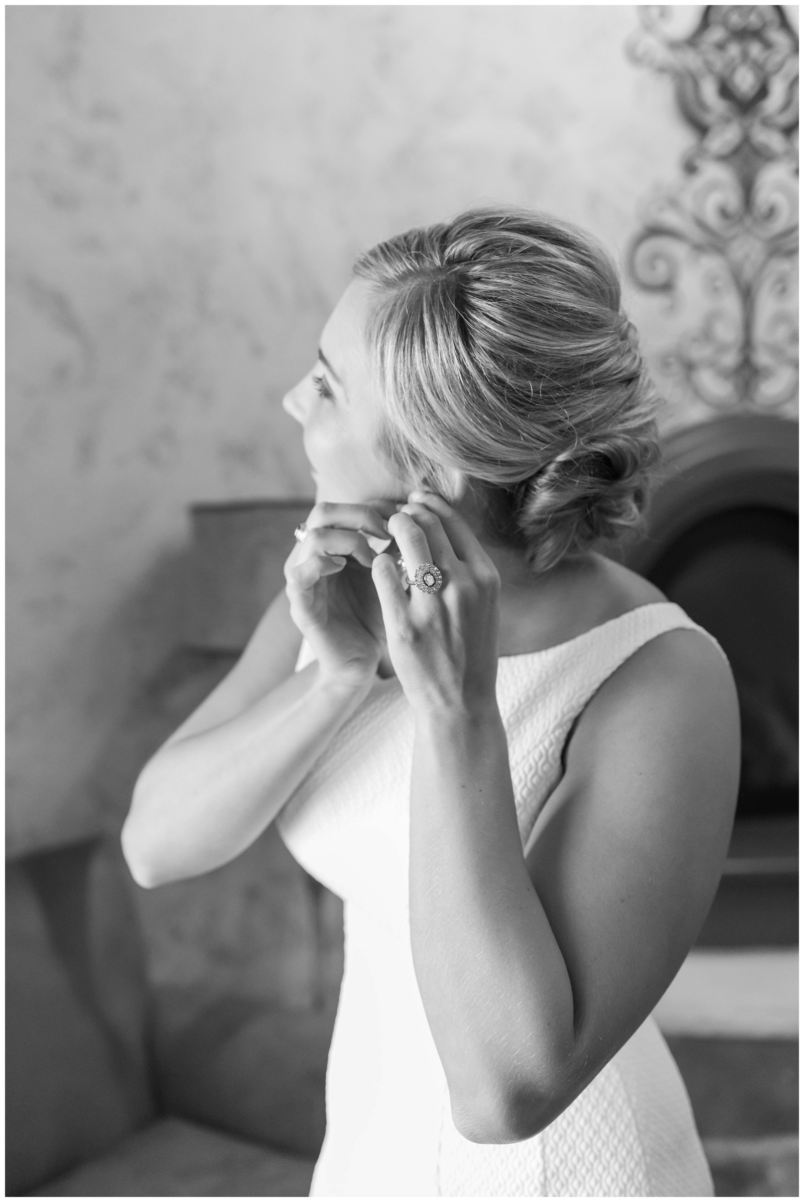 black and white portrait of bride adjusting earring in wedding dress photographed by Pipers Photography