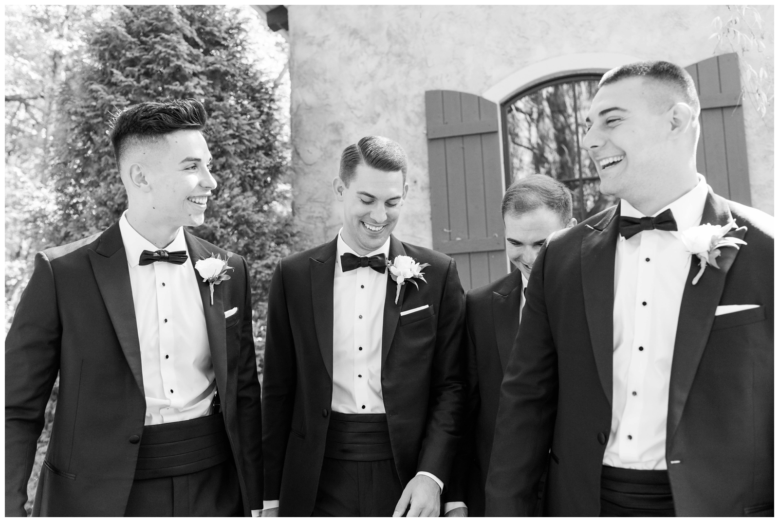 groomsmen laugh with groom in tuxes at Gervasi Vineyard