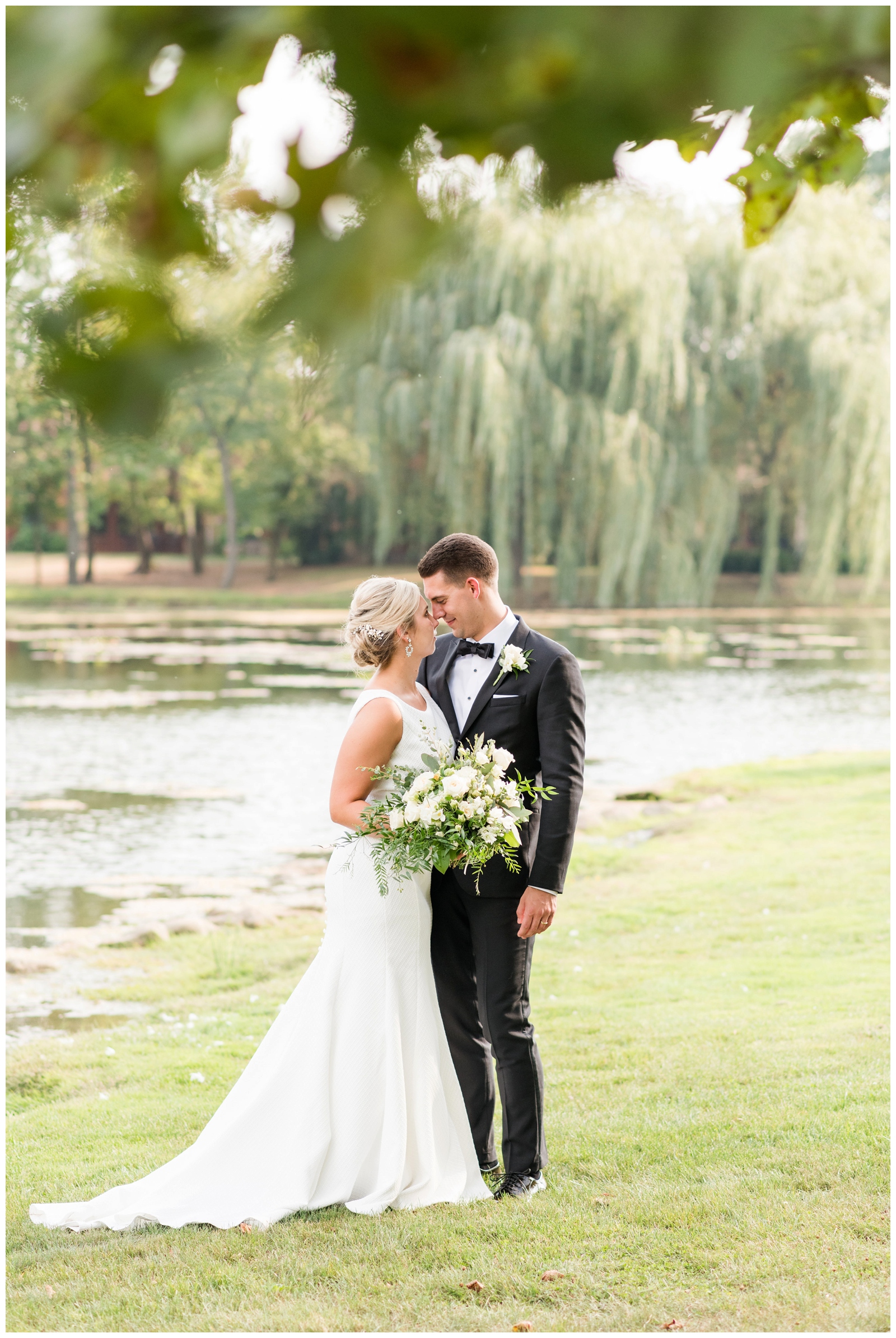 bride and groom hug near willow trees along Gervasi Vineyard pond in Canton OH